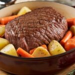 Dutch oven pot roast with tender beef, carrots, potatoes, and gravy served in a rustic cast iron pot.