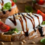 "Close-up of crispy crostini topped with creamy burrata, fresh basil, cherry tomatoes, and a drizzle of balsamic glaze."