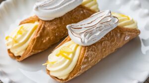 "Close-up of zesty lemon meringue cannolis with toasted meringue topping and lemon zest garnish." 