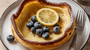 A fluffy and delicious Blueberry Lemon Dutch Baby topped with fresh blueberries and powdered sugar. Perfect for brunch or breakfast. 