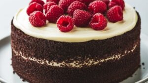 "A rich slice of decadent Black Velvet Cake with smooth cream cheese frosting on a white plate." 