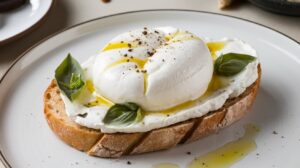 "Close-up of crispy crostini topped with creamy burrata, fresh basil, cherry tomatoes, and a drizzle of balsamic glaze."

