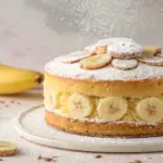 Slice of dreamy banana cake with creamy frosting and banana slices on top