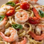 "A plate of creamy Tuscan shrimp linguine with fresh spinach and sun-dried tomatoes, garnished with Parmesan cheese and herbs."