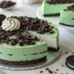 Green Velvet Oreo Cheesecake Delight with whipped cream and Oreo decorations on top, displayed on a white plate.