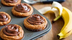 Nutella swirl banana muffins fresh out of the oven with a rich chocolate-hazelnut swirl on top.

