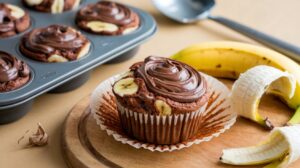 Nutella swirl banana muffins fresh out of the oven with a rich chocolate-hazelnut swirl on top.

