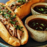 Crockpot French Dip Sandwiches with melted cheese and au jus for dipping.