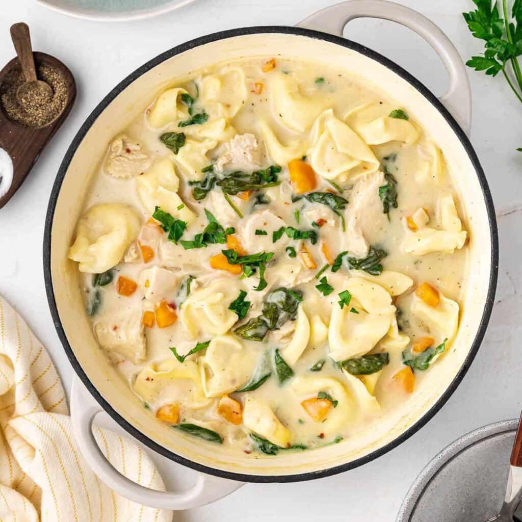 Creamy Chicken Tortellini Soup Creamy Chicken Tortellini Soup is the perfect blend of comfort, richness, and ease. With tender chicken, cheese-filled tortellini, vegetables, and a velvety cream broth, this soup delivers restaurant-quality flavor in a simple, home-cooked dish. It’s cozy enough for cold evenings yet light enough to enjoy year-round. This creamy chicken tortellini soup is especially popular because it feels indulgent without being complicated. Everything comes together in one pot, making it ideal for busy weeknights, family meals, or make-ahead lunches. Why You’ll Love Creamy Chicken Tortellini Soup This soup earns a permanent spot in your rotation because it’s: Rich and creamy without heavy techniques Hearty and filling thanks to tortellini and chicken Quick to prepare (ready in about 30 minutes) One-pot friendly with minimal cleanup Highly customizable with vegetables and seasonings It’s comfort food that feels both familiar and elevated. Ingredients You’ll Need Protein 2 cups cooked chicken (rotisserie, grilled, or poached) Salt and black pepper, to taste Pasta 1 package (18–20 oz) cheese tortellini (fresh or refrigerated) Vegetables 1 small onion, diced 2 carrots, sliced 2 celery stalks, chopped 3 cloves garlic, minced 2 cups fresh spinach (or kale) Liquids & Dairy 4 cups chicken broth (low sodium preferred) 1 cup heavy cream ½ cup whole milk (optional, for lighter texture) Seasonings 1 tsp Italian seasoning ½ tsp paprika ½ tsp black pepper Optional: red pepper flakes Step-by-Step: How to Make Creamy Chicken Tortellini Soup 1. Sauté the Aromatics Heat olive oil or butter in a large pot over medium heat Add onion, carrots, and celery Cook 5–7 minutes until softened Stir in garlic and cook 30 seconds until fragrant This step builds the flavor foundation of the soup. 2. Build the Broth Pour in chicken broth Add Italian seasoning, paprika, and pepper Bring to a gentle simmer Let the flavors meld for 5 minutes. 3. Cook the Tortellini Add tortellini directly to the pot Simmer according to package instructions (usually 3–5 minutes) Stir gently to prevent sticking Tortellini cook quickly—avoid overcooking. 4. Add Chicken and Cream Stir in cooked chicken Reduce heat to low Add heavy cream and milk (if using) Simmer gently—do not boil. 5. Finish with Greens Add spinach Cook 2–3 minutes until wilted Taste and adjust salt and seasoning Tips for the Best Creamy Chicken Tortellini Soup Use rotisserie chicken for maximum convenience Keep heat low after adding cream to prevent curdling Add tortellini near the end so they stay tender Use fresh tortellini for the best texture Variations to Try Garlic Parmesan Version Add grated Parmesan cheese at the end Tuscan-Style Soup Add sun-dried tomatoes and extra Italian herbs Lighter Version Use half-and-half instead of heavy cream Spicy Twist Add red pepper flakes or a dash of hot sauce What to Serve with Chicken Tortellini Soup This creamy chicken soup pairs beautifully with: Crusty bread or garlic knots Simple green salad with vinaigrette Grated Parmesan cheese for topping Storage, Freezing & Reheating Storage Refrigerate in airtight containers Keeps 3–4 days Reheating Reheat gently over low heat Add broth or milk if thickened Freezing Not recommended due to cream and pasta texture Best enjoyed fresh or refrigerated Common Mistakes & How to Fix Them Soup too thick? Add warm broth or milk Tortellini too soft? Added too early—reduce cook time next time Cream separated? Heat was too high Frequently Asked Questions Can I use frozen tortellini? Yes—add directly to the soup and cook a few extra minutes. Can I make this soup ahead of time? Yes, but it’s best within 1–2 days for optimal texture. Can I use uncooked chicken? Yes—simmer diced chicken in the broth before adding tortellini. Is creamy chicken tortellini soup filling? Absolutely. It’s a complete meal in one bowl. Printable Recipe Card (Quick Copy) Prep: 15 minutes Cook: 20 minutes Yield: 6 servings Sauté vegetables Simmer broth and seasoning Cook tortellini Add chicken and cream Finish with spinach Final Thoughts Creamy Chicken Tortellini Soup is the ultimate comfort-meets-convenience recipe. It’s rich, satisfying, and easy enough for any night of the week—yet special enough to serve guests. Once you try it, this cozy soup is guaranteed to become a favorite in your kitchen. 🥣